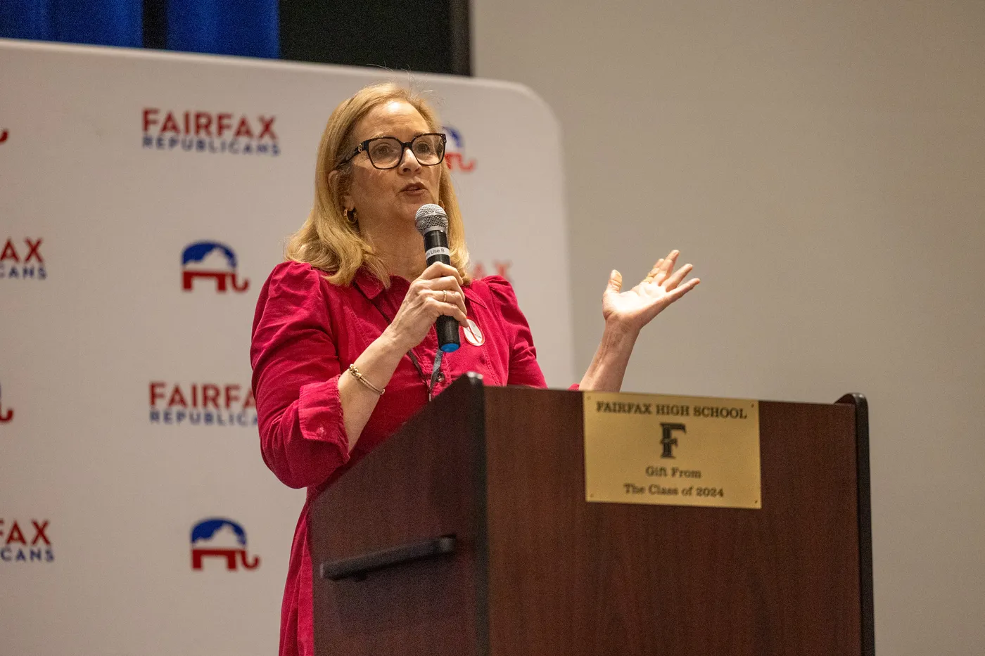 A committee leader in red speaks from the Fairfax Republicans podium at the 2026 County Convention.