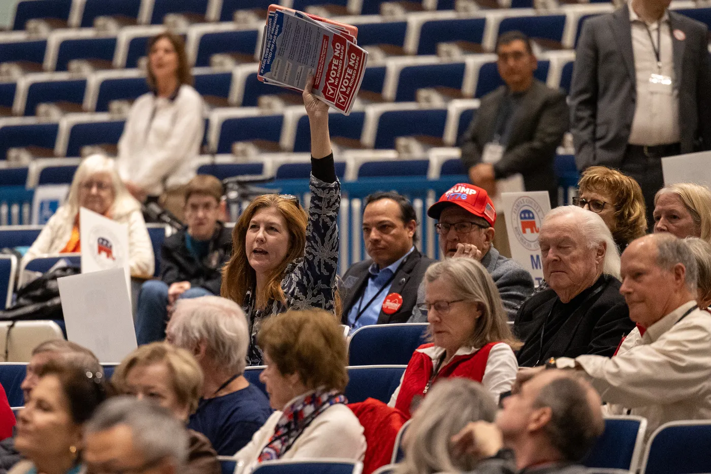 A packed auditorium of Fairfax Republicans at the 2026 County Convention, one attendee raising a red placard.