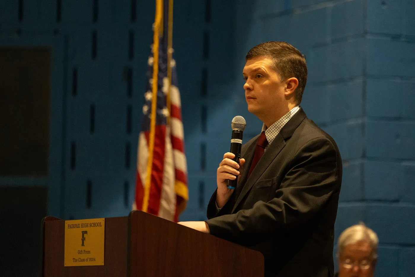 A speaker addresses the 2026 County Convention beside the American flag.